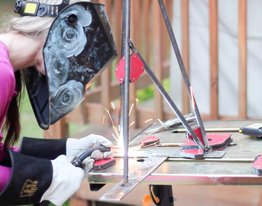 Erin Spain welding steel legs for a DIY desk.