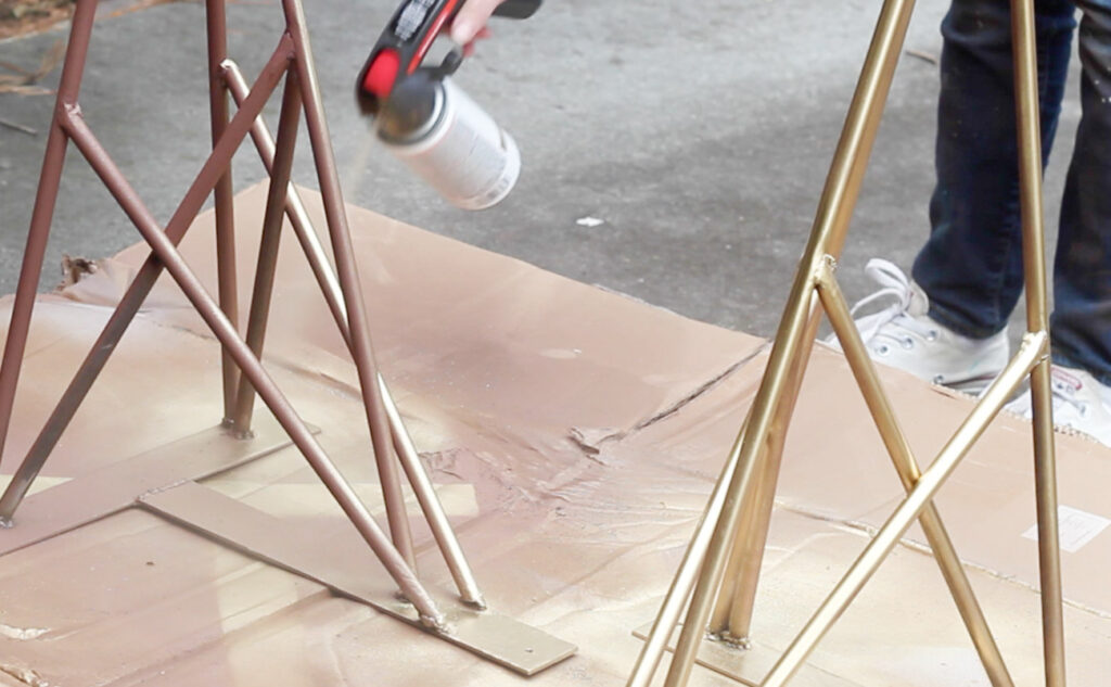 Spray painting geometric steel legs for a DIY desk.